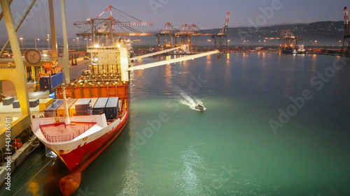 Container ship with own cranes in container terminal during cargo operations