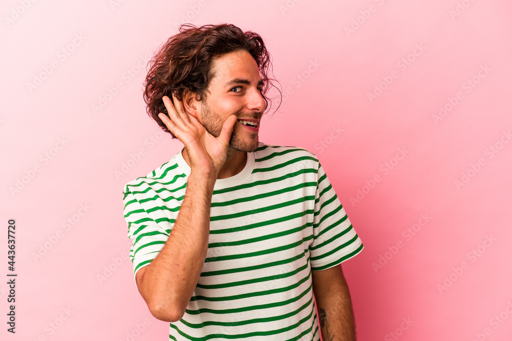 Young caucasian man isolated on pink bakcground trying to listening a gossip. Young caucasian man isolated on pink bakcground trying to listening a gossip.