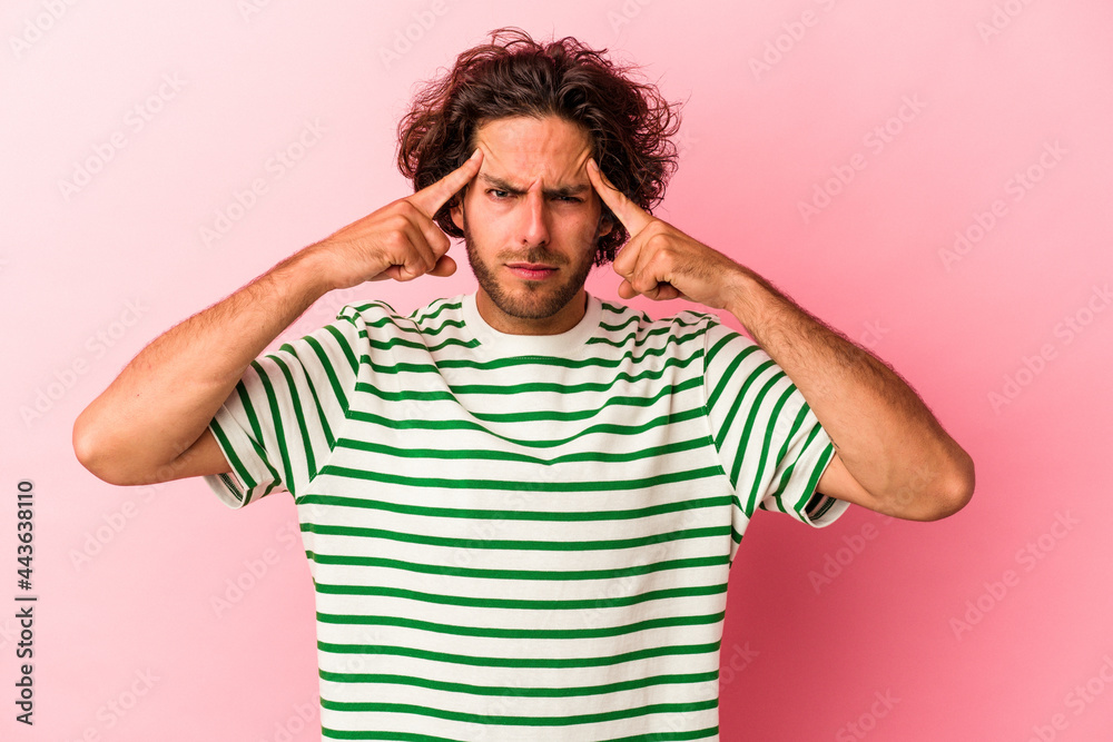 Young caucasian man isolated on pink bakcground focused on a task, keeping forefingers pointing head. Young caucasian man isolated on pink bakcground focused on a task, keeping forefingers pointing head.