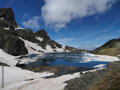 lac du petit doménon enneigé, massif de Belledonne. la neige fond et forme des gros glaçons dans le lac.