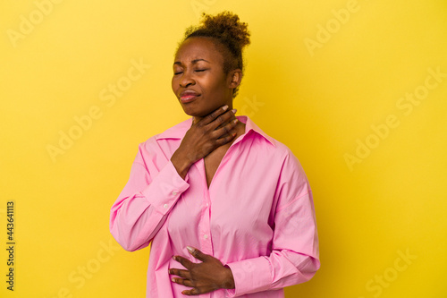 Young african american woman isolated on yellow background suffers pain in throat due a virus or infection.