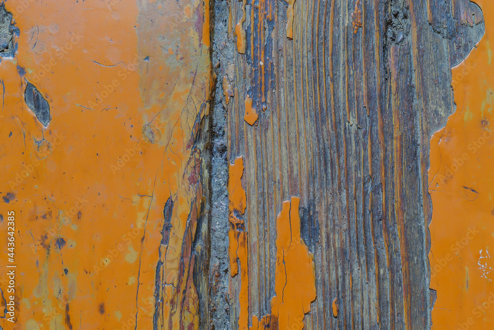 The texture of an old rustic floor with peeling orange paint