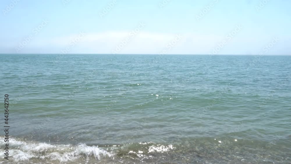 Calm Black Sea with turquoise water. Pebble beach. Close-up. Small waves roll onto shore. Horizon line is visible. Water glistens in morning sun. Beautiful marine background Calm Black Sea with turquoise water. Pebble beach. Close-up. Small waves roll onto shore. Horizon line is visible. Water glistens in morning sun. Beautiful marine background