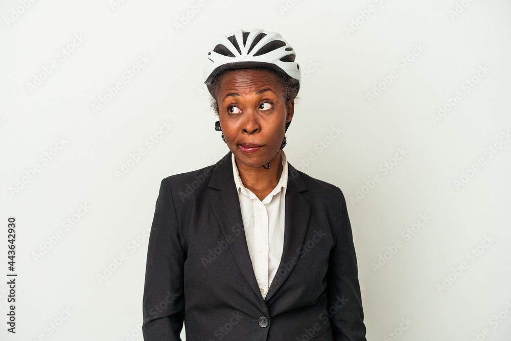 Young business african american woman wearing a bike helmet isolated on white background confused, feels doubtful and unsure. Young business african american woman wearing a bike helmet isolated on white background confused, feels doubtful and unsure.