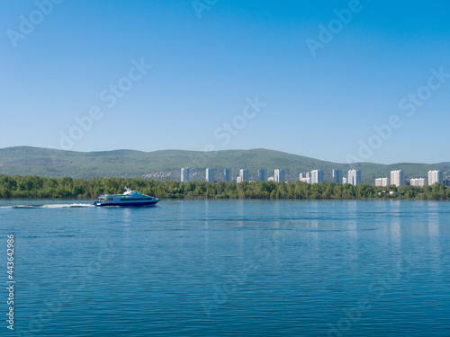 The boat sails along the Yenisei River. View of the city of Krasnoyarsk. Summer sunny day. Clear sky