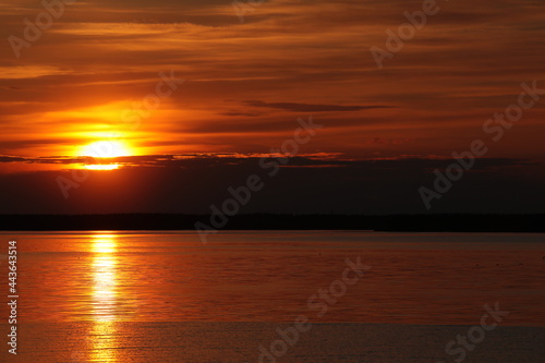 Sunset With A Golden Disk Of The Sun In A Red Sky And A Solar Trail In The Water. Nature Background © Nina