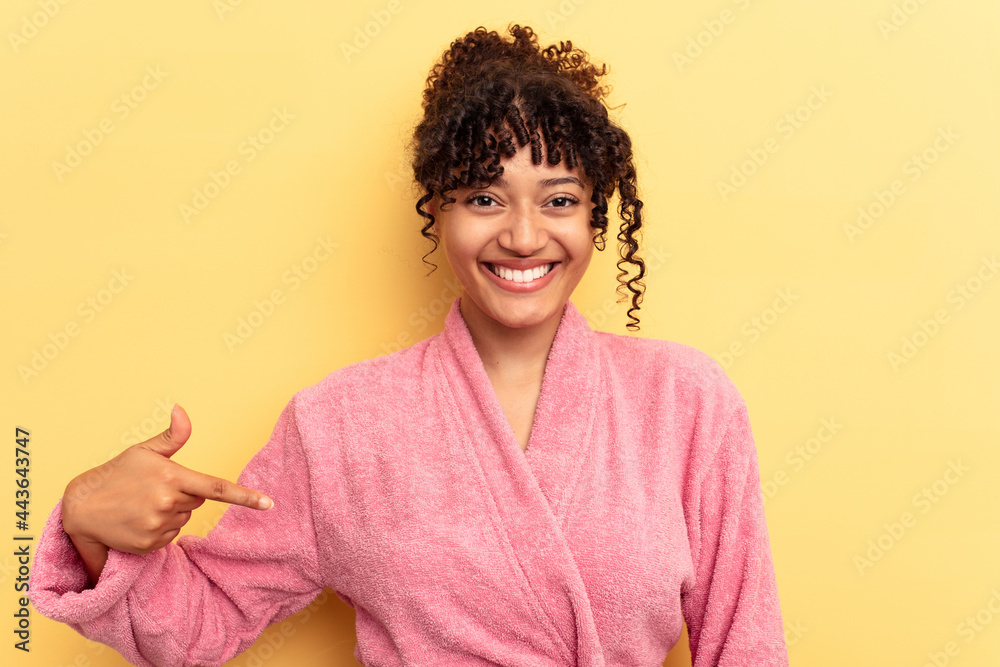 Young mixed race woman wearing a pink bathrobe isolated on pink background person pointing by hand to a shirt copy space, proud and confident Young mixed race woman wearing a pink bathrobe isolated on pink background person pointing by hand to a shirt copy space, proud and confident