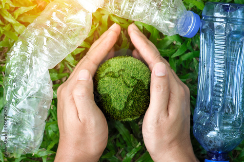 Obraz na plátně top view of hands holding protect the earth from plastic bottle waste on a green background