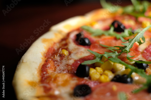Pizza close up. Salami, corn, olives, greens