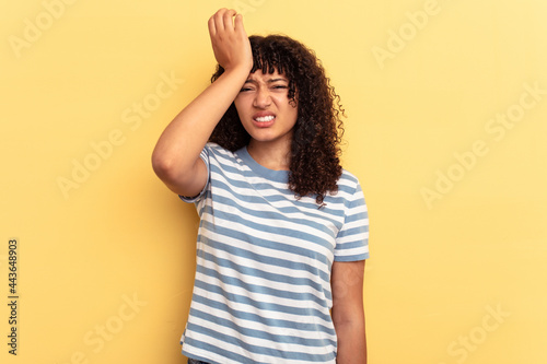Young mixed race woman isolated on yellow background forgetting something, slapping forehead with palm and closing eyes.