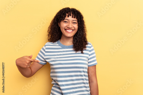 Young mixed race woman isolated on yellow background person pointing by hand to a shirt copy space, proud and confident © Asier