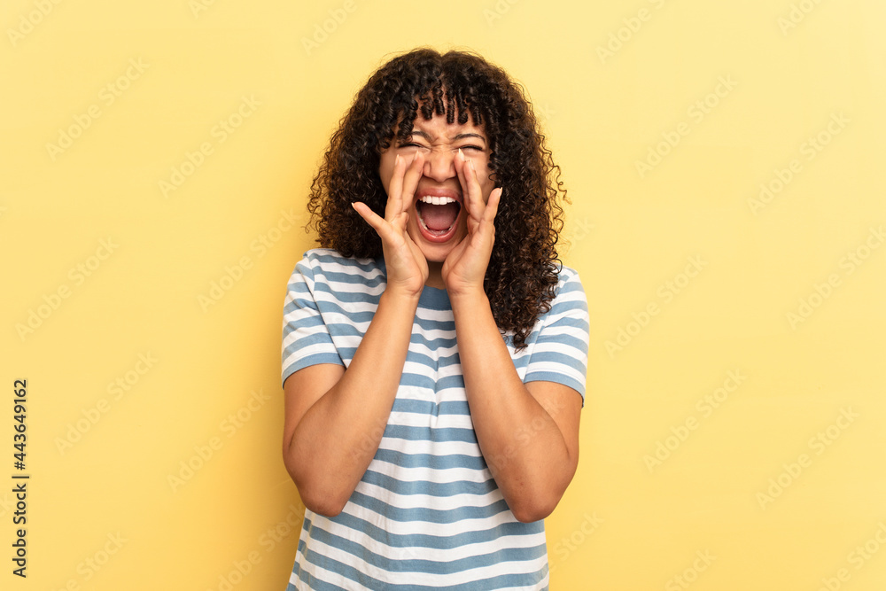 Young mixed race woman isolated on yellow background shouting excited to front. Young mixed race woman isolated on yellow background shouting excited to front.