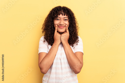 Young mixed race woman isolated on yellow background doubting between two options.