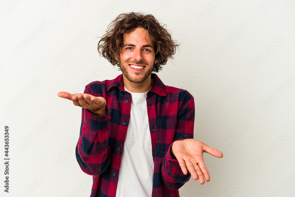 Young caucasian man isolated on white background makes scale with arms, feels happy and confident. Young caucasian man isolated on white background makes scale with arms, feels happy and confident.
