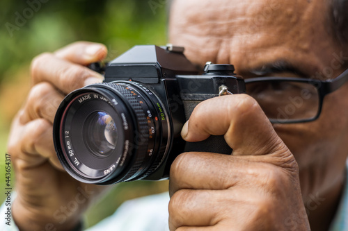 Close-up of an elderly man taking pictures with an old film camera.