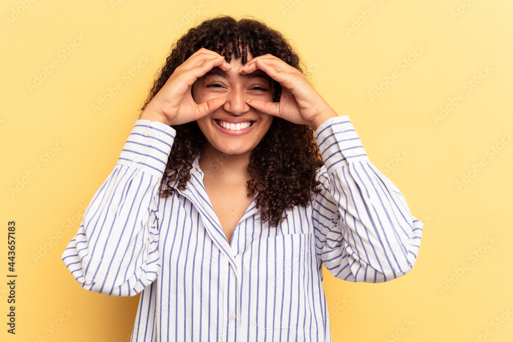 Young mixed race woman isolated on yellow background showing okay sign over eyes Young mixed race woman isolated on yellow background showing okay sign over eyes