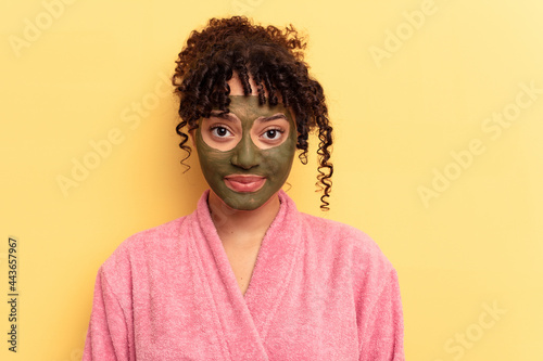 Young mixed race wearing facial mask isolated on yellow background