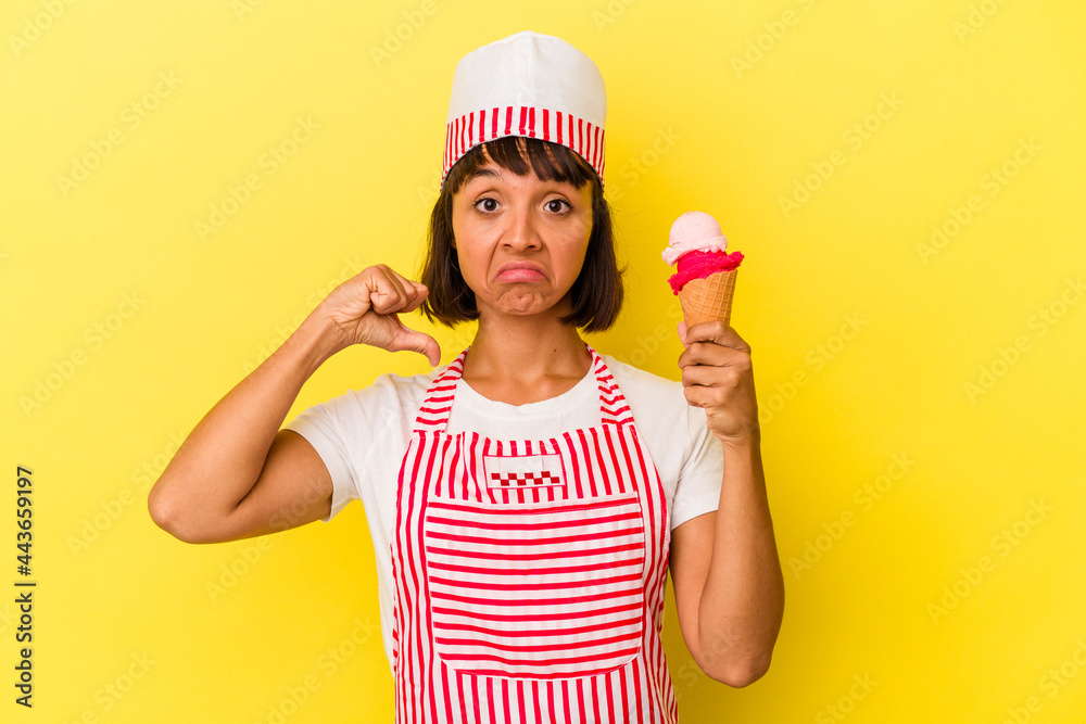Young mixed race ice cream maker woman holding an ice cream isolated on yellow background feels proud and self confident, example to follow. Young mixed race ice cream maker woman holding an ice cream isolated on yellow background feels proud and self confident, example to follow.