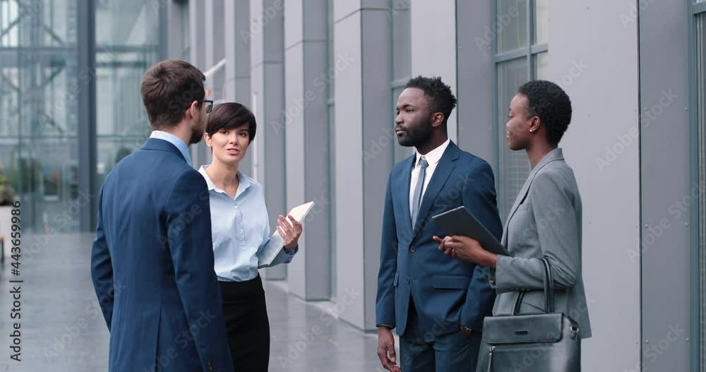 Glad to hear it. Portrait of optimistic young qualified managers is looking at each other with smile while standing at the street and having pleasant communication Glad to hear it. Portrait of optimistic young qualified managers is looking at each other with smile while standing at the street and having pleasant communication
