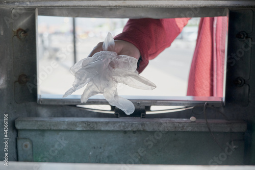 Woman hand throws protective gloves against the virus into the trash. The concept of lifting lockdown restrictions and ending virus pandemic. The camera shoots out of the basket. Hands close up shot