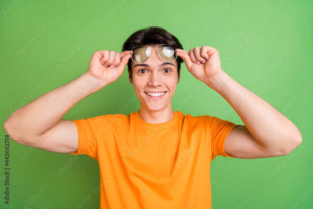 Photo of happy cheerful young positive man wear sunglass good mood news isolated on green color background Photo of happy cheerful young positive man wear sunglass good mood news isolated on green color background