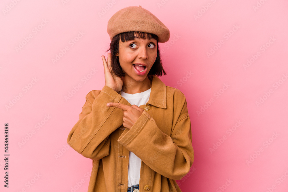 Young mixed race woman isolated on pink background trying to listening a gossip. Young mixed race woman isolated on pink background trying to listening a gossip.