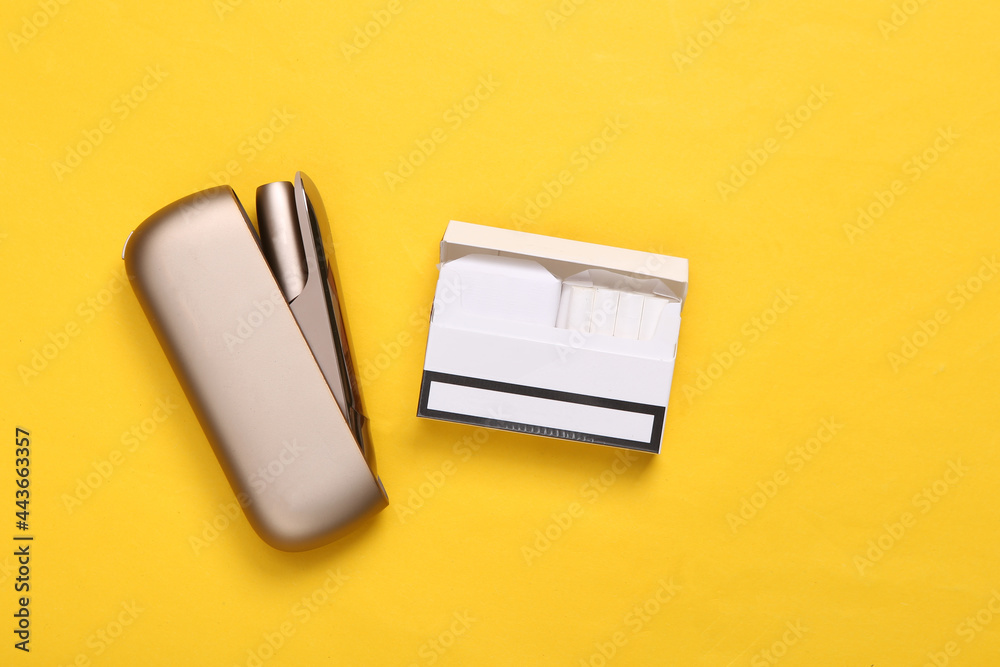 Tobacco heating system and pack of sticks .on yellow background. Top view Tobacco heating system and pack of sticks .on yellow background. Top view