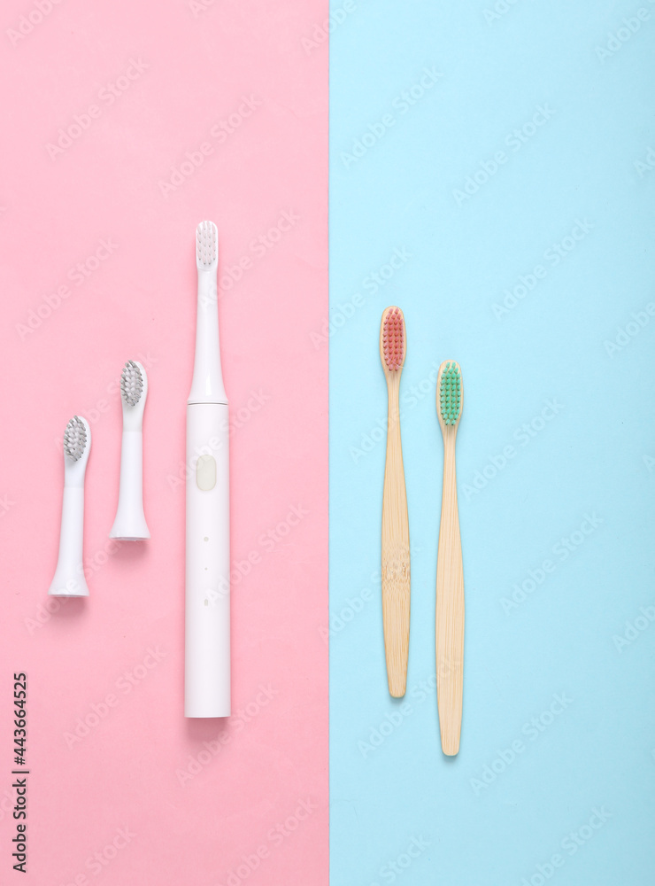 Ultrasonic plastic toothbrush and eco bamboo toothbrushes on blue pink pastel background