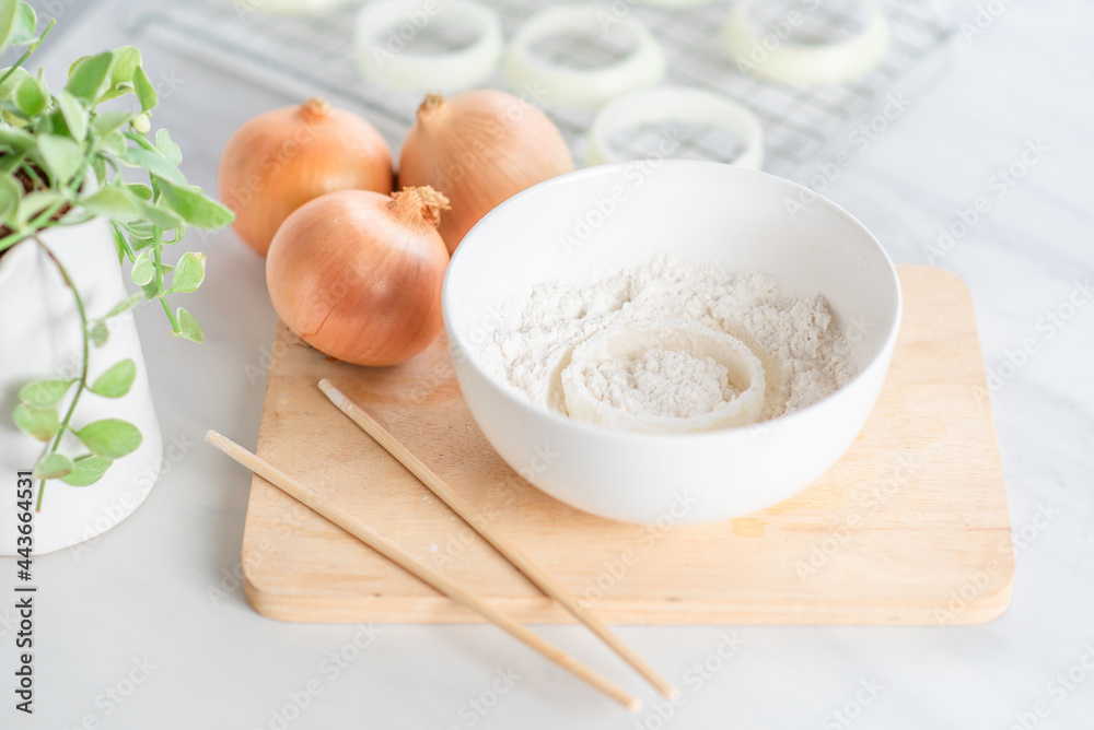 Fresh raw onion rings and flour on cutting board. Fresh raw onion rings and flour on cutting board.