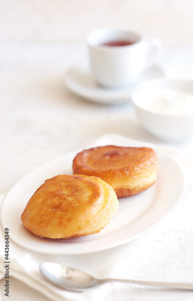 Pancakes are in a plate on the table, behind sour cream and tea. Nice breakfast Pancakes are in a plate on the table, behind sour cream and tea. Nice breakfast