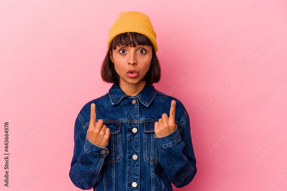 Young mixed race woman isolated on pink background pointing upside with opened mouth. Young mixed race woman isolated on pink background pointing upside with opened mouth.