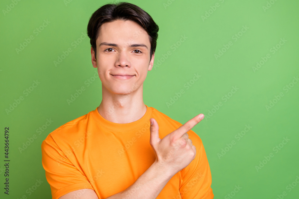 Photo of happy cheerful young man point finger empty space sale recommend isolated on green color background Photo of happy cheerful young man point finger empty space sale recommend isolated on green color background