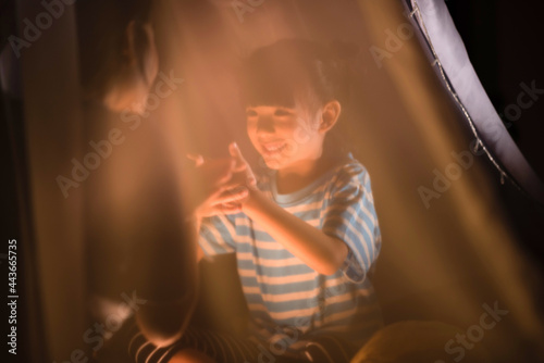 a little girl playing hand shadow art with her mom in bedroom before sleeping time, family concept, cute kid smiling, asian family concept, playing in kid tent.