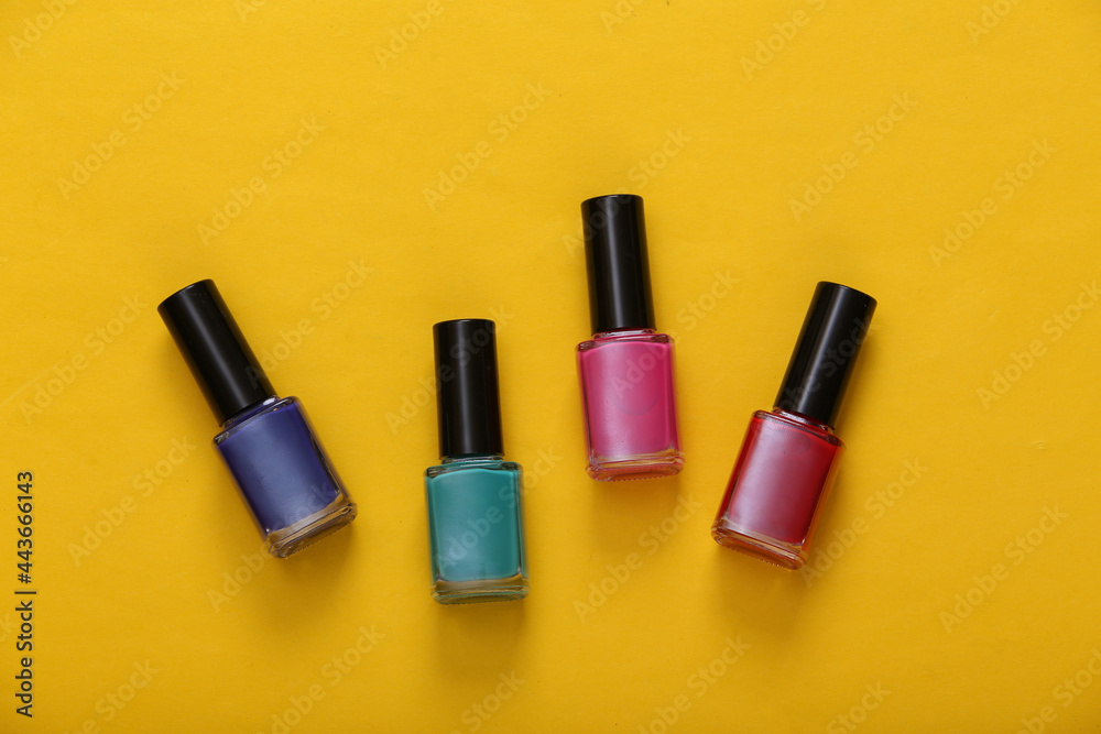 Bottles of colored nail polish on yellow background. Top view Bottles of colored nail polish on yellow background. Top view