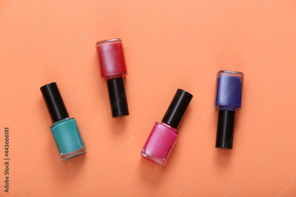 Obraz premium Bottles of colored nail polish on orange background. Top view