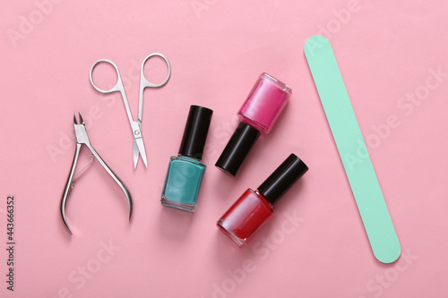 Manicure accessories. Nail polish bottles, scissors and nail file on pink background. Top view. Flat lay
