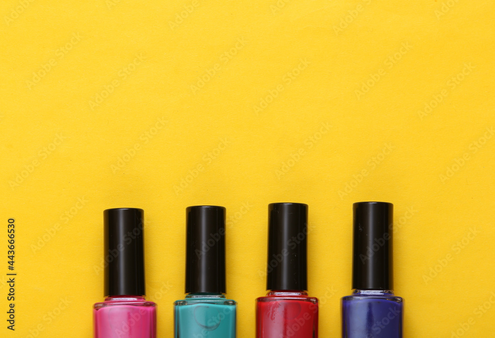 Bottles of colored nail polish on yellow background. Top view Bottles of colored nail polish on yellow background. Top view