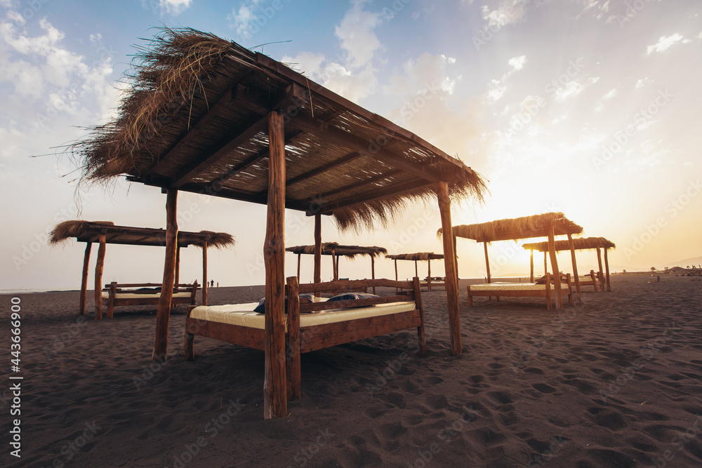 Fototapeta premium Sandy beach with sun beds at sunset