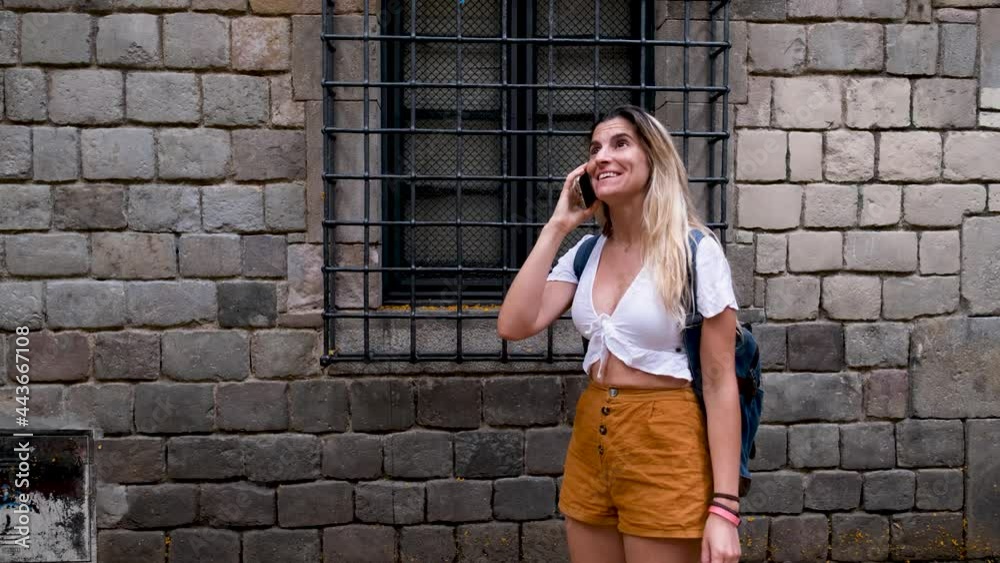 Woman talks with her mobile phone while walking down the street of Barcelona The woman is smiling and very pretty Woman talks with her mobile phone while walking down the street of Barcelona The woman is smiling and very pretty