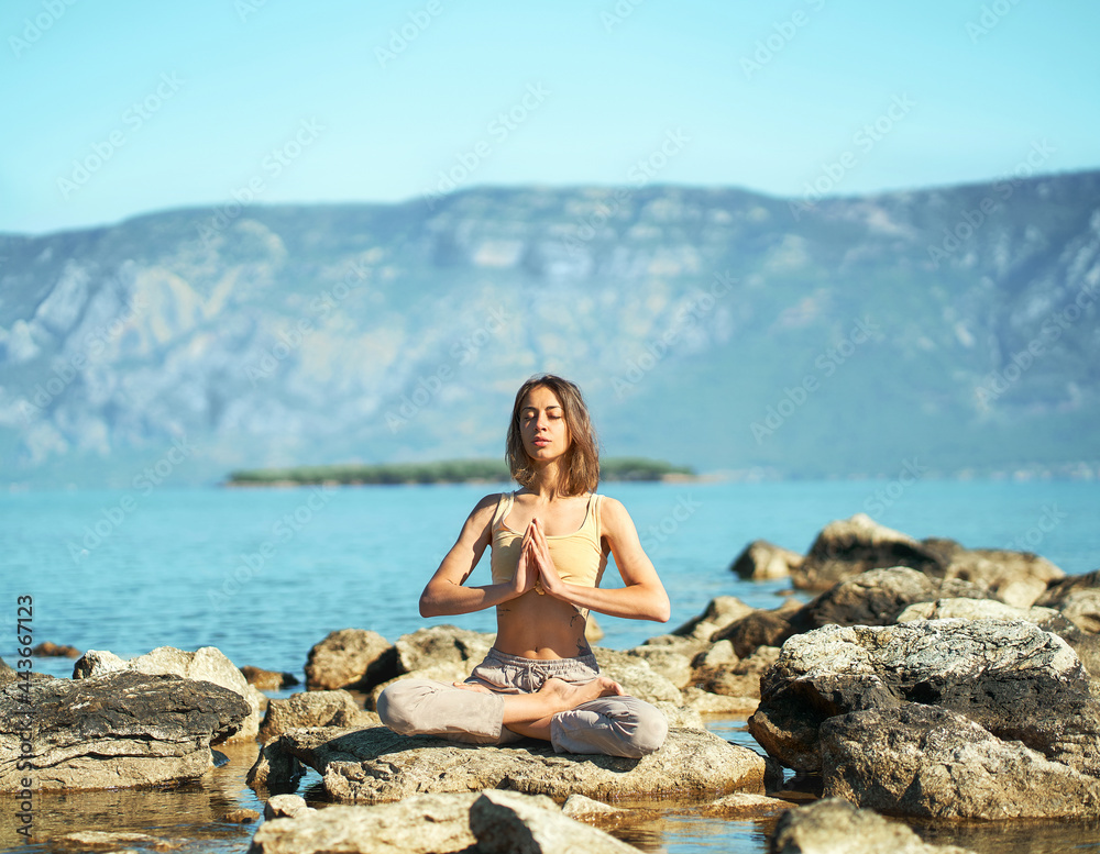 Morning maditation and yoga in beautiful mountains landscape, healthy woman sitting in asana Namaste Lotus pose with eyes closed