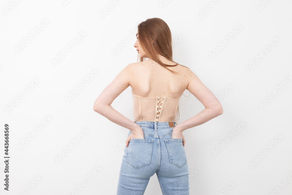 Back view of sexy stylish woman in jeans and corset on white background Back view of sexy stylish woman in jeans and corset on white background