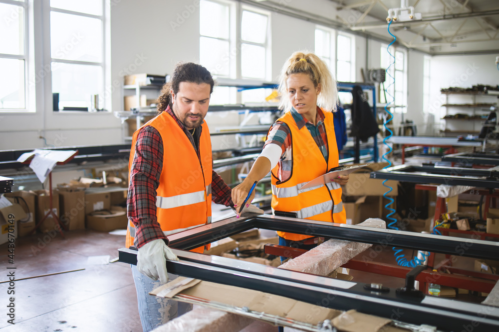 Manual worker assembling PVC doors and windows with his colleague. Factory for aluminum and PVC windows and doors production. Manual worker assembling PVC doors and windows with his colleague. Factory for aluminum and PVC windows and doors production.