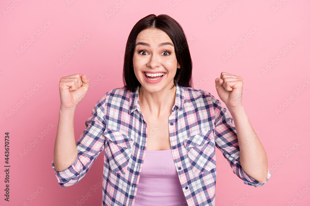 Photo of grateful young millennial lady hands fists wear plaid shirt isolated on pink color background Photo of grateful young millennial lady hands fists wear plaid shirt isolated on pink color background