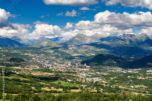 Fototapeta Naklejka Na Ścianę i Meble -  The city of Gap in Summer with view of the distant mountains of the Ecrins National Park massif. Hautes-Alpes in the French Alps. France