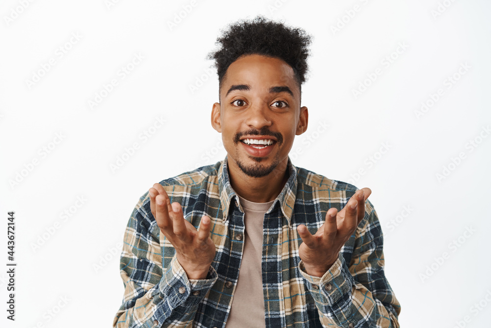 Close up portrait of happy african american man looking surprised and proud of you, raising hands as if holding smth in empty palms, making announcement, white background
