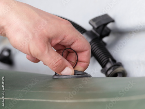 A man's hand opens the valve cover for deflating an inflatable boat closeup