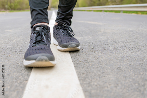 Morning run. Running feet while running, Runner in black sneakers runs on the asphalt.