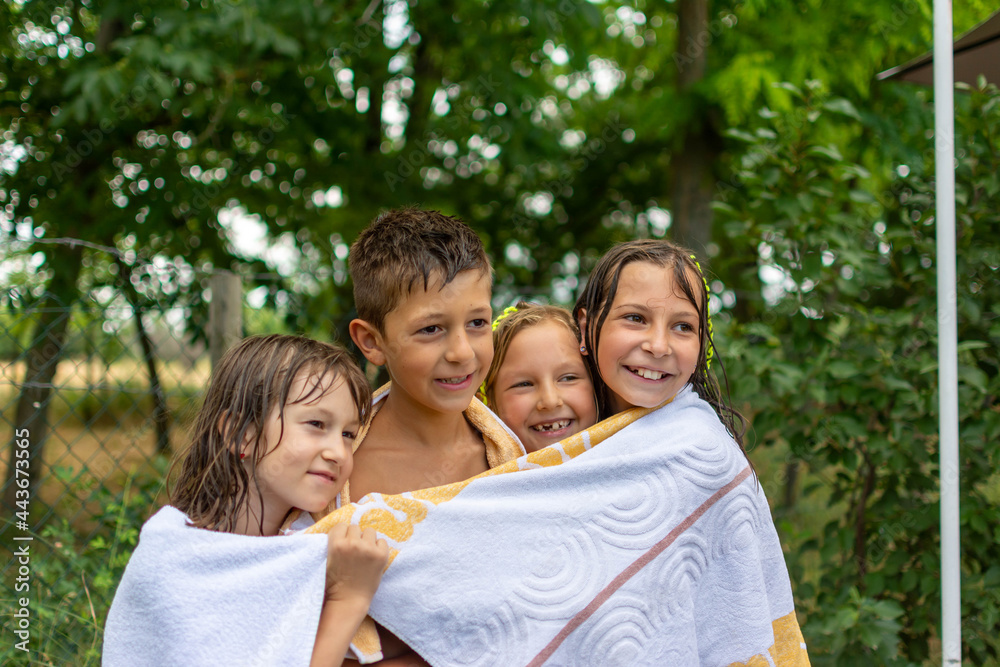 happy children wrapped in a towel after swimming in the outdoor pool in nature. After swimming, the children were wrapped in a towel
