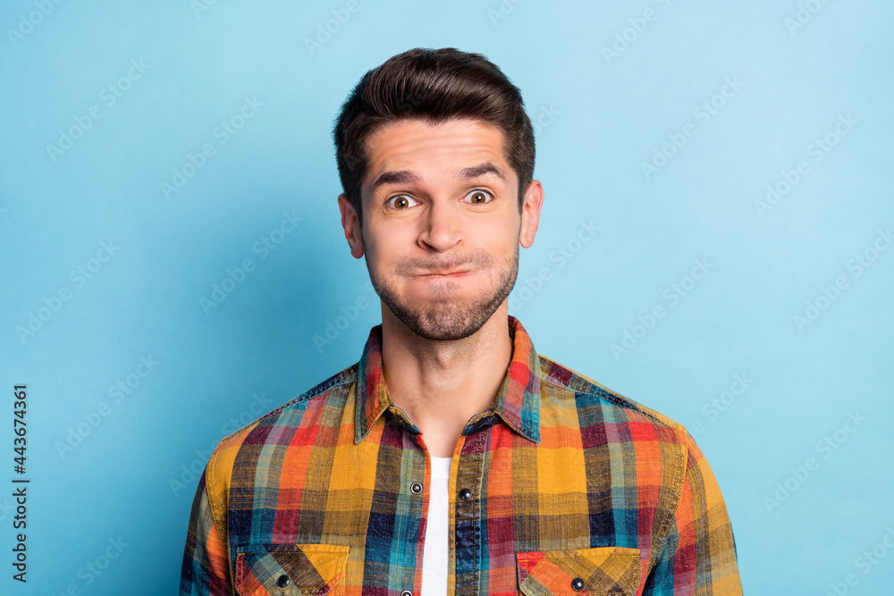 Portrait of attractive playful cheerful brunette guy wearing checked shirt grimacing isolated over bright blue color background Portrait of attractive playful cheerful brunette guy wearing checked shirt grimacing isolated over bright blue color background