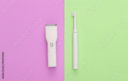 Hair clipper and toothbrush on a pink green pastel background. Top view © splitov27